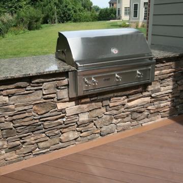 Built-in stainless grill with stone veneer base on deck