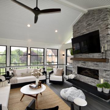 Three season room with stone fireplace, TV, and black framed windows