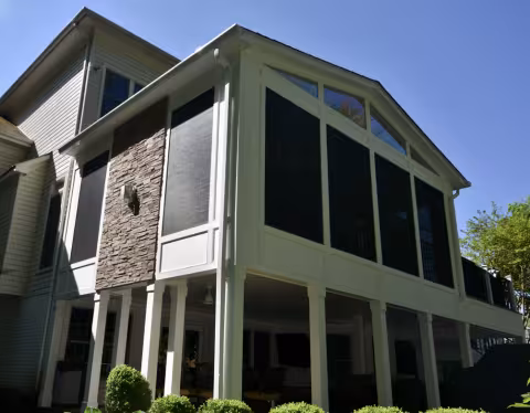 Two-story screened porch with gabled roof and stone accent wall