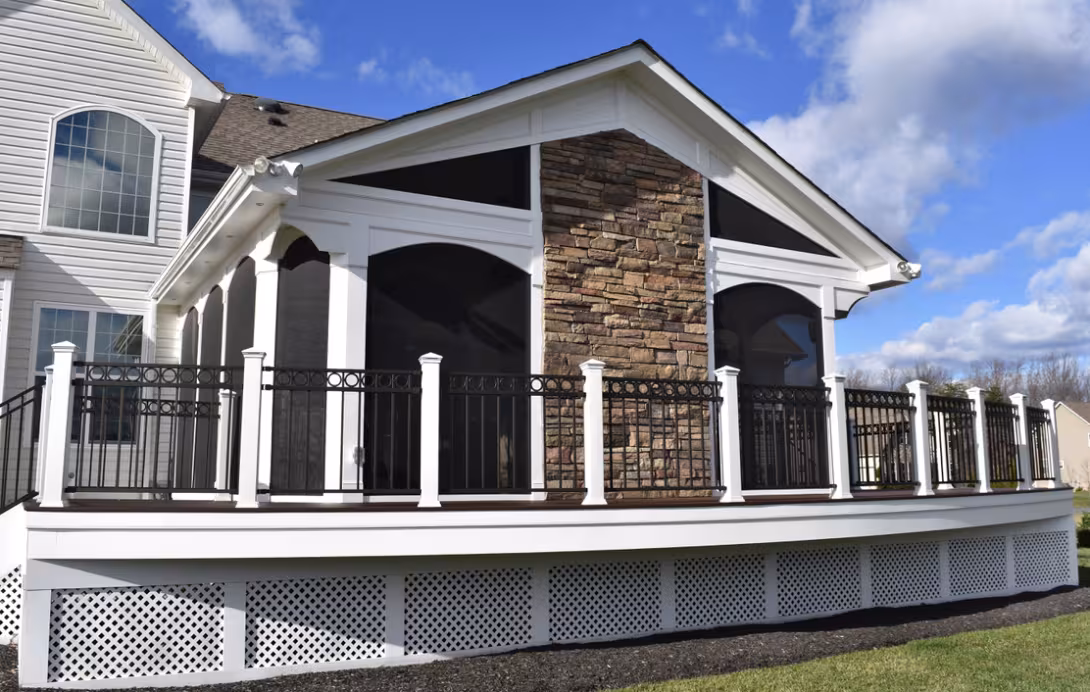 Large screened porch with stone chimney and wraparound deck railing